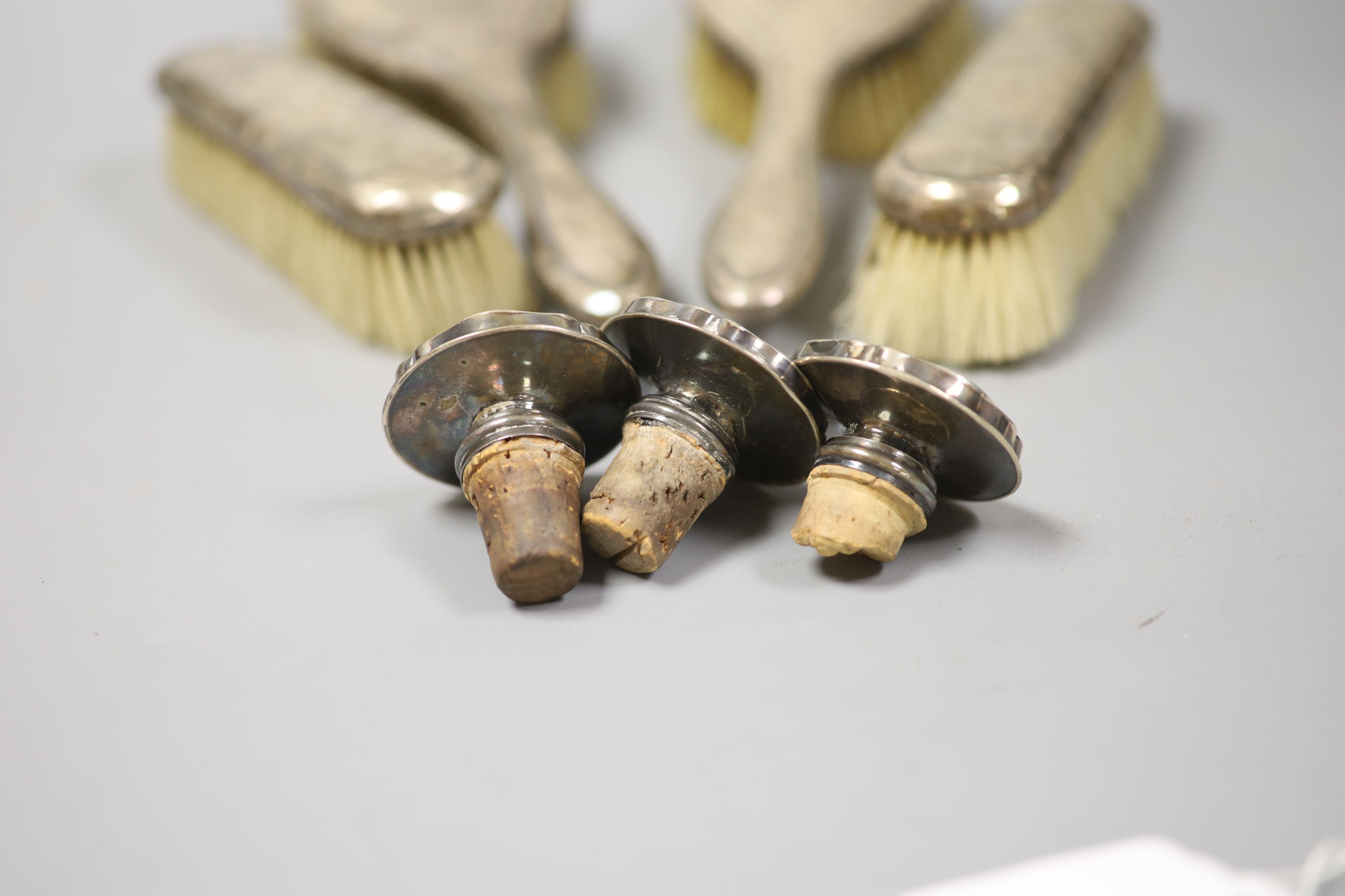 Four silver mounted brushes and three 830s mounted stoppers.